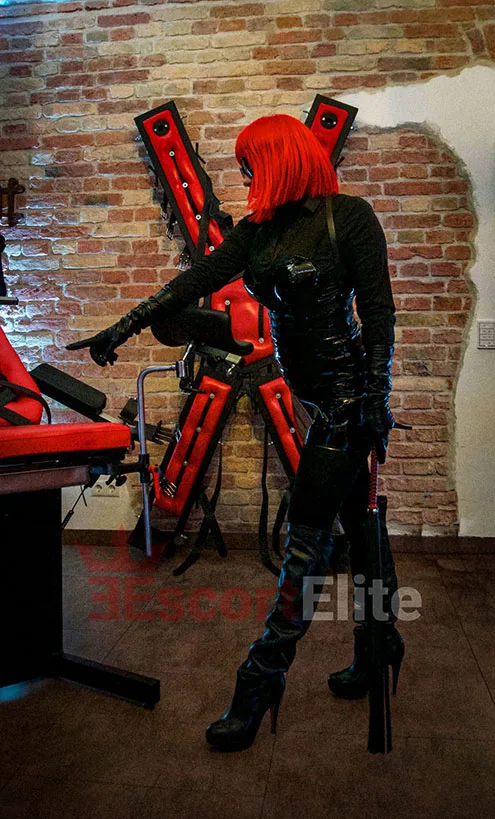 Dominatrix Viena con fusta en estudio SM sobre mesa traje de látex