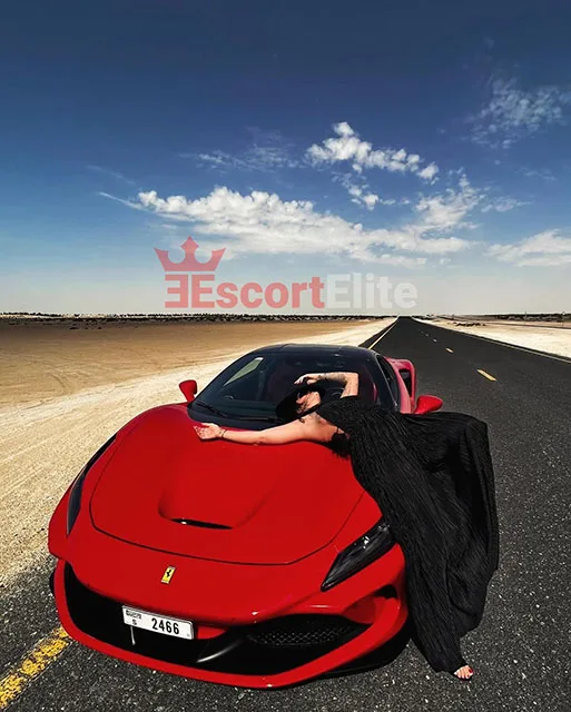 Escort Vienne Rossa sur une Ferrari rouge dans une pose élégante dans le désert