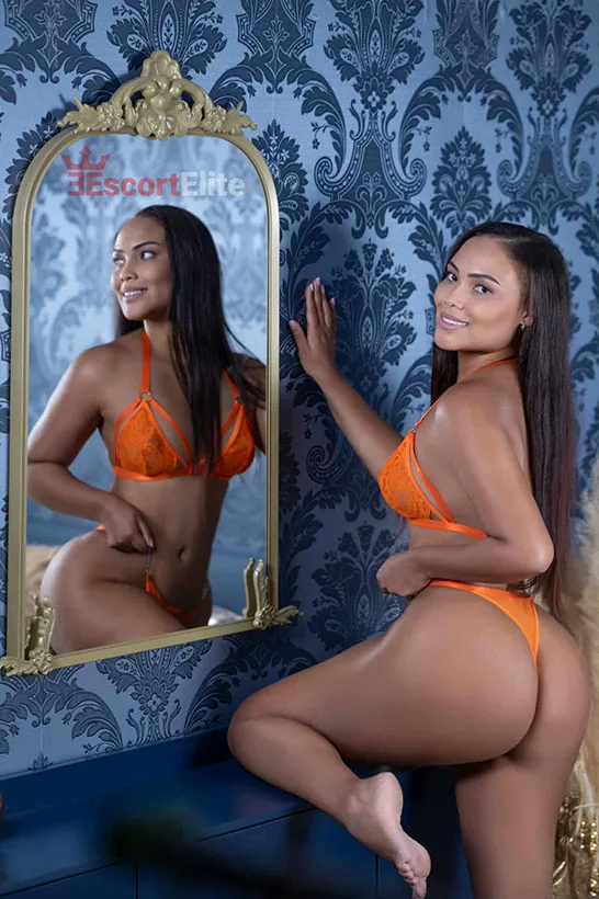 Escort latina Viena Naty ante un espejo lujoso en lencería elegante